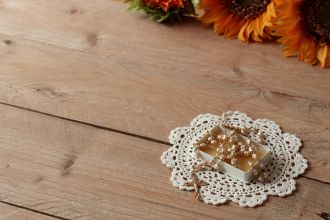 A rosary on a lace doily on a wooden table, adorned with sunflowers. Perfect for religious themes.